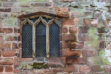 Kurşun ışıkları ve yıpranmış kilise duvarları olan eski İngiliz kilisesi penceresi..