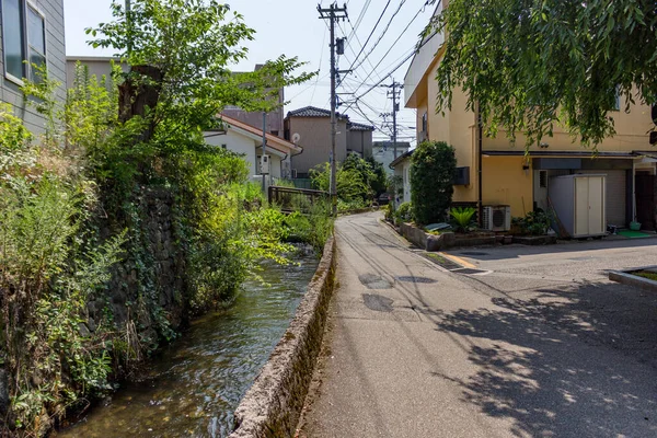 Summer view of small back street with watercourse, downtown Kanazawa, Japan.