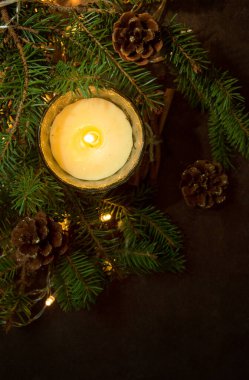 Mutlu Noeller ve yeni yıl konsepti, yakın plan, köknar dallarıyla süslenmiş zarif Noel mumu koyu bir arka planda koyu renkli bir anahtar.