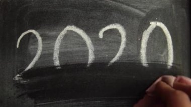 2020 yılında, erkek eli tebeşiri tebeşir tabağında bir parça tebeşirle ıslak bir bezle sildi.