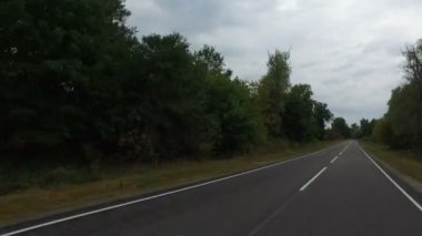 Akşama doğru. Terk edilmiş bir köyde, sık ağaçların arasında terk edilmiş kırsal evlerin arasında pürüzsüz asfalt yol