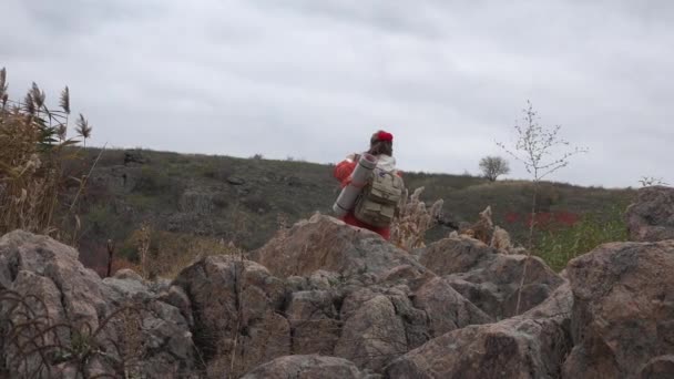 背中の後ろに赤いジャケットを着た熟女は 秋の山の中で自然のスマートフォンから写真を撮る場所を選択します — ストック動画