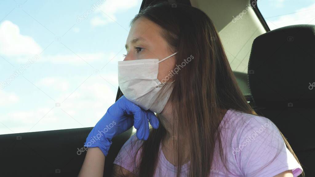 A girl in a car wearing a medical mask and blue gloves to prevent the spread of COVID-19. Riding a woman wearing a respirator to protect against the flu virus. Pandemic