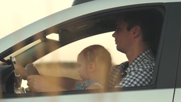 Papa leert zijn dochtertje om het stuur te draaien terwijl ze in zijn auto zit in de bestuurdersstoel. Vader reist met kinderen met de auto. Bestuurder en kind rijden. gelukkig familie en jeugd concept — Stockvideo