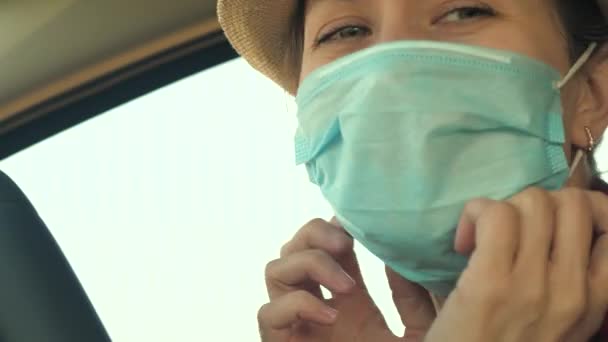 Młoda kobieta prowadzi samochód w masce medycznej, aby zapobiec rozprzestrzenianiu się COVID-19. Prowadzenie kobiety z maską na twarzy w samochodzie w celu ochrony przed wirusową grypą — Wideo stockowe