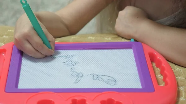 Een klein meisje leert tekenen op het schoolbord. Ontwikkeling van motoriek voor kinderen. Kinderen vermakelijke spelletjes. Solo lessen. Het concept van kinderontwikkeling. Close-up — Stockfoto