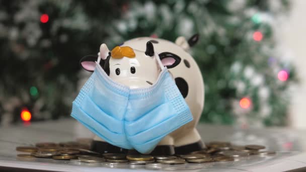 Piggy bankovní figurka ve formě krávy nebo býka v lékařské masce. Dopad pandemie na hospodářství. Ruce s prasátko banky close-up — Stock video