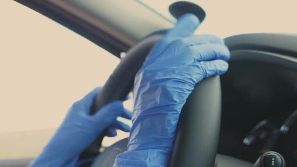 Dziewczyna w medycznych niebieskich rękawiczkach obraca kierownicą samochodu. Ochrona przed wirusem Covid-19. Pandemia. Zbliżenie — Wideo stockowe