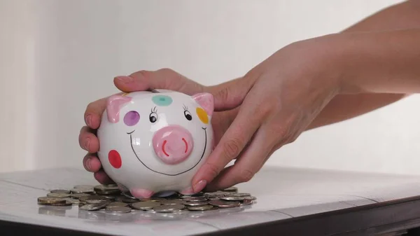 Das Sparschweingeschäft steht auf einem Haufen Münzen. Eine Hand steckt eine Münze in ein Lifestyle-Sparschwein auf gelbem Hintergrund. Geld zu sparen ist eine Investition in die Zukunft. Bankeninvestitionen. — Stockfoto