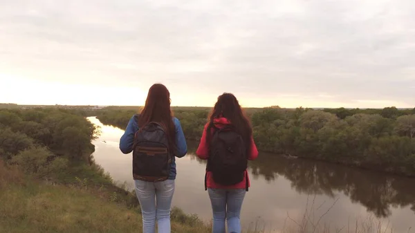 女朋友们背着背包在河边旅行.快乐的女游客正在寻找冒险.团队合作。在女人们的运动远足周末。休息一下吧地形研究 — 图库照片