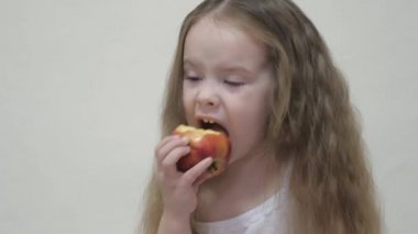 Küçük bir kız kırmızı bir elmayı ısırır ve çiğner. Çocuklar için sağlıklı beslenme. Vitamin meyvesi. Çocukluk tadı. Yakın plan. Çocuk lezzetli yemekler yiyor. İyi bir bağırsak yolu için yiyecek.