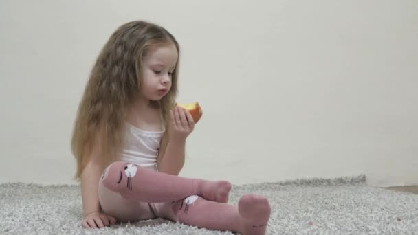 Ένα κοριτσάκι δαγκώνει ένα κόκκινο μήλο και μασάει. Υγιεινή διατροφή για παιδιά. Βιταμίνη. Γεύση παιδικής ηλικίας. Κοντινό πλάνο. Το παιδί τρώει νόστιμο φαγητό. Τροφή για ένα καλό εντερικό σωλήνα — Αρχείο Βίντεο