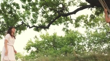 Mutlu kızlar salıncakta sallanıyor ve gülüyorlar. Anne ve kızı bir yaz günü parkta oynarlar. Doğada yürü. Aile değerleri. Kavram. Takım çalışması. Havada süzül