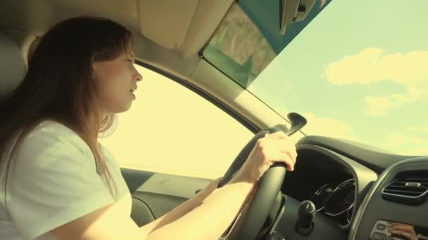 Νεαρή γυναίκα που οδηγεί αυτοκίνητο ή τροχόσπιτο ταξιδεύει στην εξοχή. Το κορίτσι είναι μόνο στο μεταγωγικό. Τραγουδάει τη μελωδία του τραγουδιού, τις δονήσεις των καλοκαιρινών διακοπών — Αρχείο Βίντεο