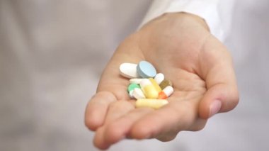Beyaz önlüklü bir sağlık çalışanının elinde bir sürü renkli hap vardı. Ebedi gençliğin ve sağlığın ilacı. Hastaların iyileşmesi. Hastalıkların tedavisi. Yakın plan.