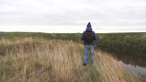 En man resenär går längs vägen med ryggen med en ryggsäck. En man går på en vandring. Letar efter äventyr på nya platser. Upptäck världen och lev som turist. En turist promenad längs — Stockvideo