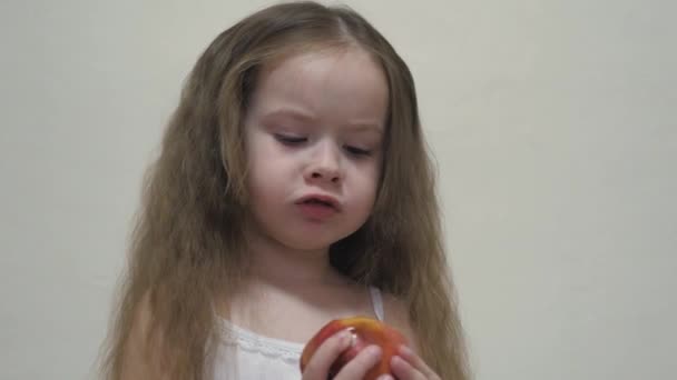 Mała dziewczynka gryzie czerwone jabłko i żuje. Zdrowa dieta dla dzieci. Owoce witaminy. Smak dzieciństwa. Zbliżenie. Dziecko je pyszne jedzenie. Żywność dla dobrego przewodu pokarmowego — Wideo stockowe