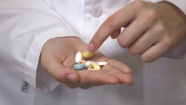 Болеутоляющие таблетки в женской руке врача в белом халате. Капсулы с лекарствами, прием лекарств, здравоохранение, аптека и концепция лечения, близкое рассмотрение — стоковое видео