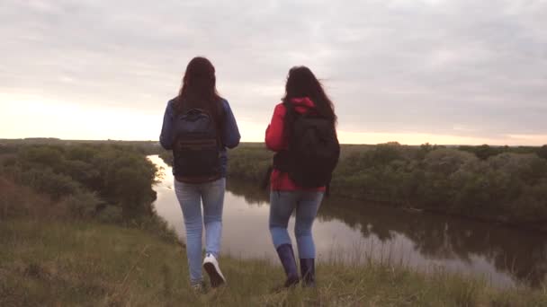 Les copines voyagent avec des sacs à dos au bord de la rivière. Filles gaies touristes sont à la recherche d'aventure. Travail d'équipe. Week-end de randonnée sportive entre les femmes. Repose-toi dans la nature. Recherche sur le terrain — Video