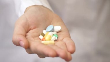 Beyaz önlüklü bir tıp uzmanının elinde ağrı kesici haplar. İlaçlı kapsüller, ilaçlar, sağlık hizmetleri, eczane ve tedavi konsepti, yakın görüş