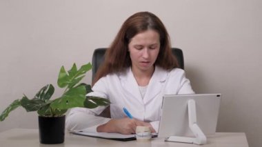 Tablet kullanan bir dişçiyle çevrimiçi görüşme. Kadın ortodontist sıva dişleri tutuyor ve elini ısırıyor. Uzman bir doktor muayenehanesinde çene tedavisi. Sağlıklı ve güzel bir gülümseme