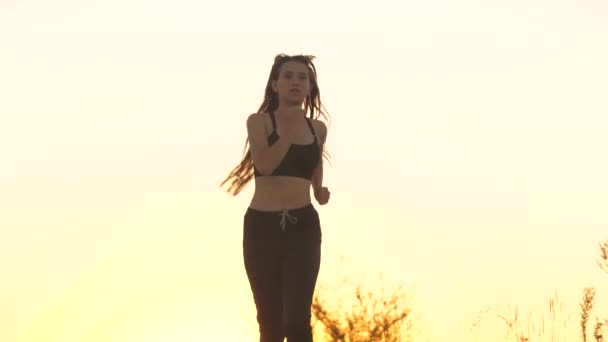 Une jeune sportive court au coucher du soleil heureuse et souriante. Jolie fille qui court. Activités sportives. Il fait de la croix. J'adore le jogging extérieur. Minceur et corps mince. Mode de vie sain. Liberté sautante — Video