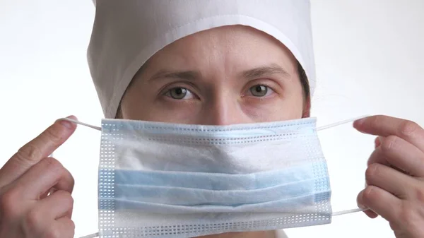 Женщина-врач в белом халате надевает маску на лицо. Крупный план. Дышите через воздушную фильтрацию. Защита от вирусов и респираторных заболеваний — стоковое фото