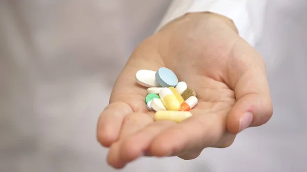 Many colored pills in the female hands of a medical worker in a white coat. The medicine of eternal youth and health. Recovery of the sick. Treatment of diseases. Close-up