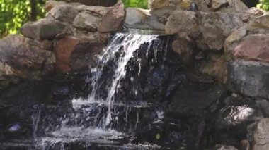 Saf temiz su doğadaki taşlardan yavaşça akar. Uçan spreyli küçük şelale