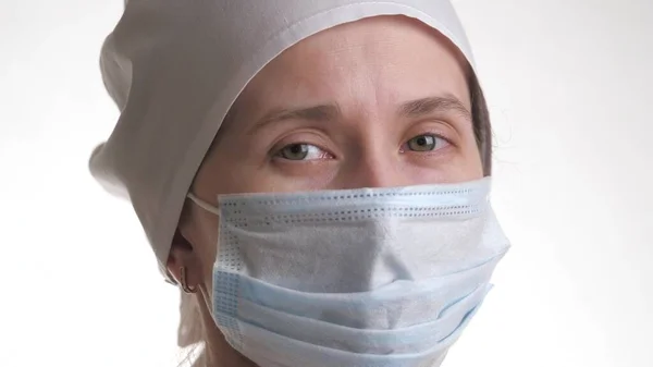 Медицинский работник надевает маску и улыбается. Портрет медицинского персонала крупным планом. Женщина в защитной маске. Изолирована на белом фоне. Здравоохранение и медицинское понятие. Крупный план — стоковое фото