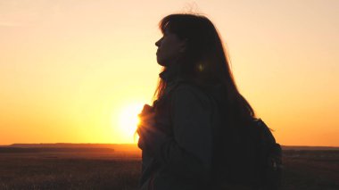 Gün batımında sırt çantalı bir gezgin kız gökyüzüne bakar ve dua eder. Bir kadın harika bir hayat hayal eder. Orman yürüyüşünde maceraperest. Hafta sonu parkta yürüyüş.