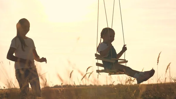 Amusement park dream concept. Happy girl swinging on a swing in the park at sunset. child plays with wooden swing, childhood dream, airplane pilot flights to the sky. A happy family — Stock Photo, Image