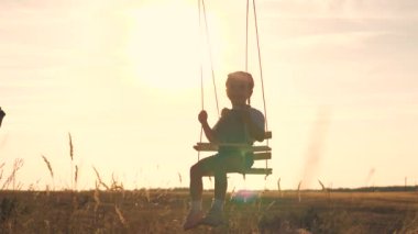 Lunapark rüyası konsepti. Gün batımında parkta sallanan mutlu kız. Çocuk ahşap salıncakla oynuyor, çocukluk hayali, uçak pilotu gökyüzüne uçuyor. Mutlu bir aile.