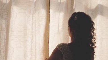 Sabahın sıcak ışığı için perdeyi çekiyorlar. Ağır çekim. Yatak odasında perdeleri açan genç bir kadın. - Yakın çekim. Sabahları eller pencerenin perdesini açar