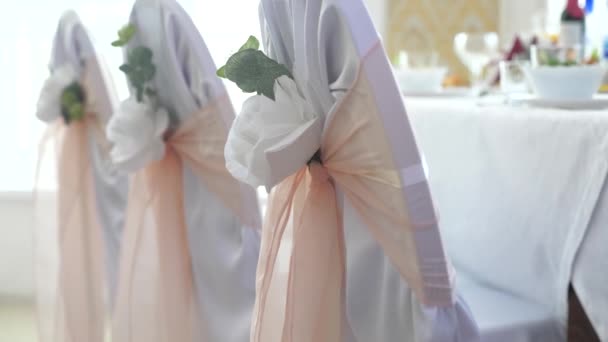 Décor avec des roses blanches et des rubans roses sur des chaises blanches vides en préparation de la cérémonie de mariage. Décoration colorée fond cérémonie de mariage concept festif — Video