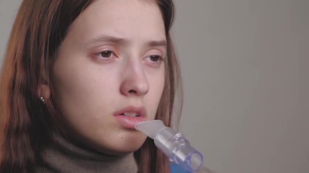 少女は肺の吸入のための溶液中で呼吸する。隔離された若い女性は薬で蒸気を吸入することによって咳を治療します.寒さのための専門的な設備を備えた自宅での人の治療 — ストック動画