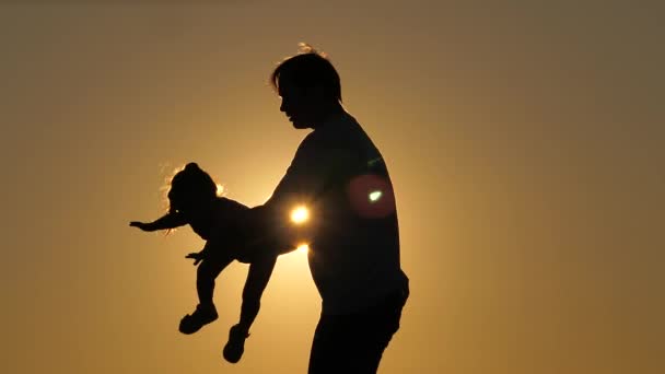 Silhouette du jour du papa avec fille au coucher du soleil. La fille vole dans les bras de son père, les bras sur les côtés. La jeune fille s'envole dans le ciel dans les bras de son parent bien-aimé. Séparation de — Video
