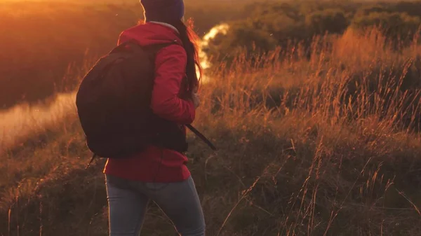 Chica feliz turista con una mochila camina por la montaña al amanecer y sonríe. Busca viajes de aventura por la zona. El camino de la vida como una forma de vida. Mujer en una caminata deportiva. Un hombre libre en la naturaleza —  Fotos de Stock