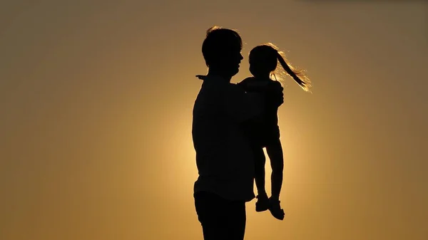 Silueta de día de papá con hija al atardecer. La hija vuela en los brazos de su padre con los brazos hacia los lados. La niña se eleva en el cielo en los brazos de su amado padre. Separación de —  Fotos de Stock