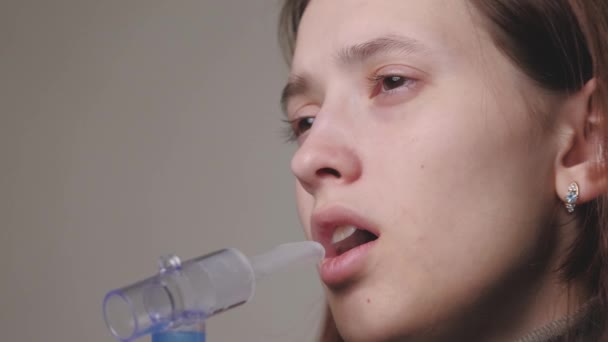 De vrouw met de bril gebruikt de inhalator en haalt diep adem. Portret van het meisje met vernevelaar. Thema van het gebruik van medische hulpmiddelen in behandeling. — Stockvideo