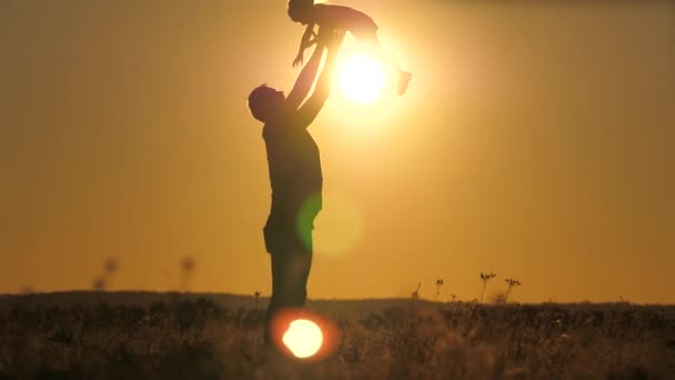 Силуэт папа бросает счастливую маленькую дочь в закатное небо. День Отцов. Ребенок хочет летать над землей. Родитель с ребенком играет на рассвете. Концепция семьи и детства. Малыш прыгает на — стоковое видео