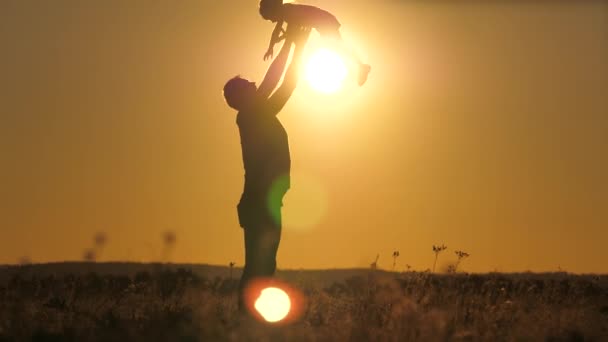 Silhouette papa jette heureuse petite fille dans le ciel couchant. La fête des pères. L'enfant veut voler au-dessus du sol. Un parent avec un enfant joue à l'aube. Concept de famille et d'enfance. Le gamin saute dessus — Video