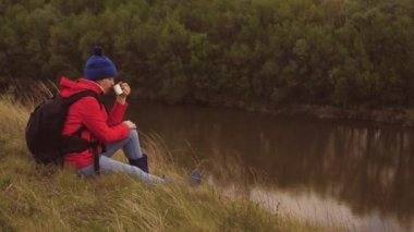 Sırt çantalı bir kız elinde bir kupa sıcak çayla doğanın tadını çıkarıyor. Tek başına kamp yapan bir kadın. Farklı ülkelere seyahat etmeyi severim. Evden uzakta tek başına dinlenmek. Hayal et ve