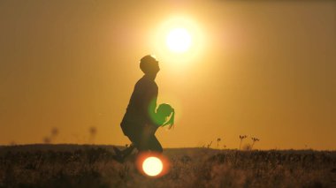 Siluet babası mutlu küçük kızını gün batımında gökyüzüne fırlattı. Babalar Günü. Çocuk yerin üstünde uçmak istiyor. Çocuklu bir ebeveyn şafakta oynar. Aile ve çocukluk kavramı. Çocuk atlıyor.