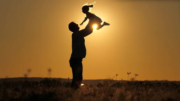 Silhouette papà getta felice figlioletta nel cielo del tramonto. Festa dei padri. Il bambino vuole volare sopra la terra. Un genitore con un bambino gioca all'alba. Concetto di famiglia e infanzia. Il ragazzo salta su — Foto Stock