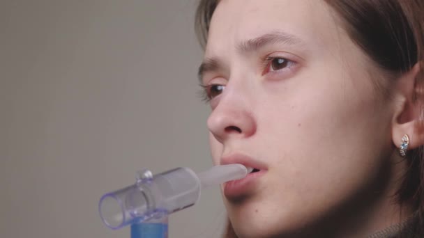 La niña inhala una solución para la inhalación de pulmones. Una mujer joven en cuarentena trata la tos inhalando vapor con medicamentos. Tratamiento de una persona en el hogar con equipo profesional para resfriados — Vídeo de stock