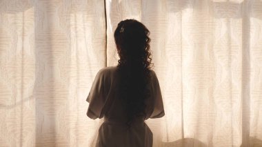 Sabahın sıcak ışığı için perdeyi çekiyorlar. Ağır çekim. Yatak odasında perdeleri açan genç bir kadın. - Yakın çekim. Sabahları eller pencerenin perdesini açar