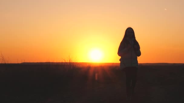 Een meidenreiziger loopt met een rugzak op haar rug en glimlacht bij zonsondergang in de lucht. Een tiener op kampeervakantie. Jeugd op zoek naar avontuur van 's ochtends tot' s morgens vroeg. Liefde voor de — Stockvideo