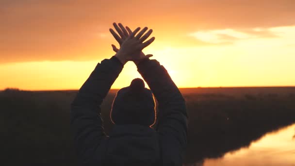 Een man zwaait met zijn handen bij zonsondergang en vraagt om hulp, gered van het gevaar te verdwalen. Man in de schittering van de zon springt. Man bij zonsopgang op kampeervakantie of alleen op reis — Stockvideo