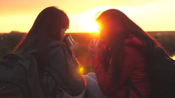 Belle ragazze al tramonto bere bevande calde. Donne felici viaggiatrici. Le persone in escursione si riposano. Vacanza turistica congiunta nella natura. La felicita 'di stare insieme lontano da casa. Riunioni familiari e — Foto Stock